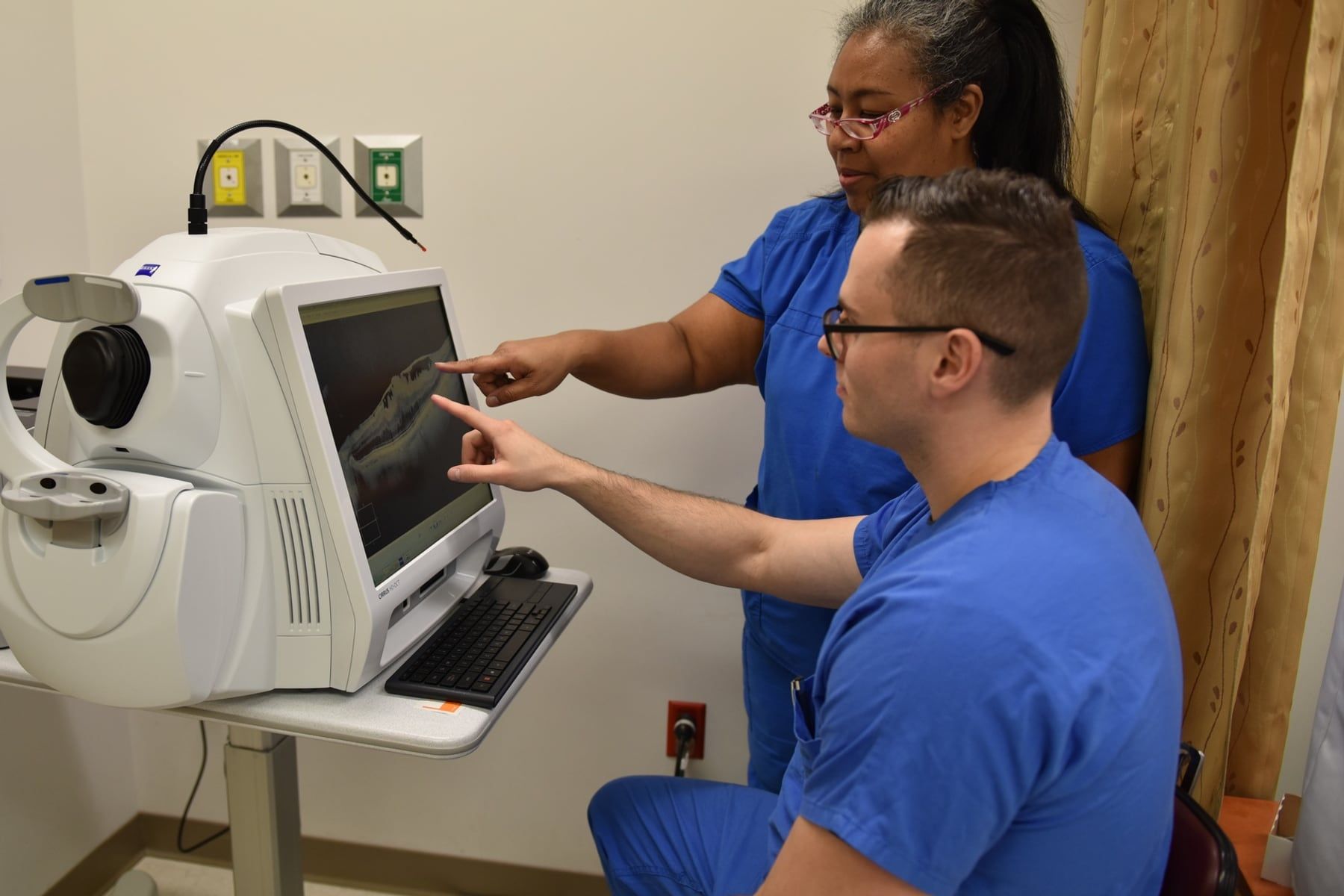 Eye-care clinicians reviewing a retinal OCT cross-sectional scan